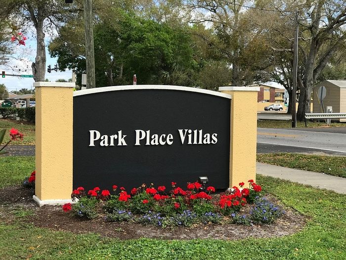 Inviting entrance sign of Park Place Villas surrounded by vibrant red flowers and lush greenery.