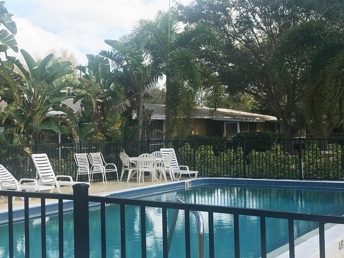 Inviting outdoor pool area surrounded by lush greenery and elegant white loungers, perfect for relaxation.