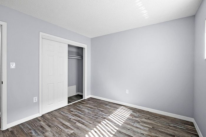 Bright and airy bedroom featuring sleek hardwood floors and a spacious closet with sliding doors. Perfect for modern living.