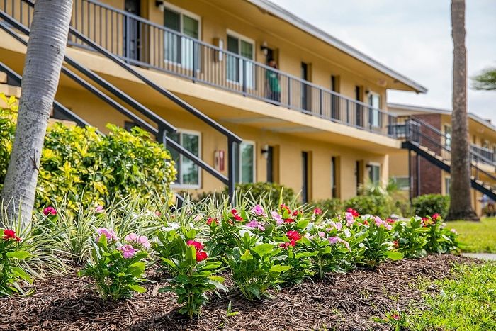Charming apartment complex with vibrant flower beds and modern architecture, offering a tranquil living environment.