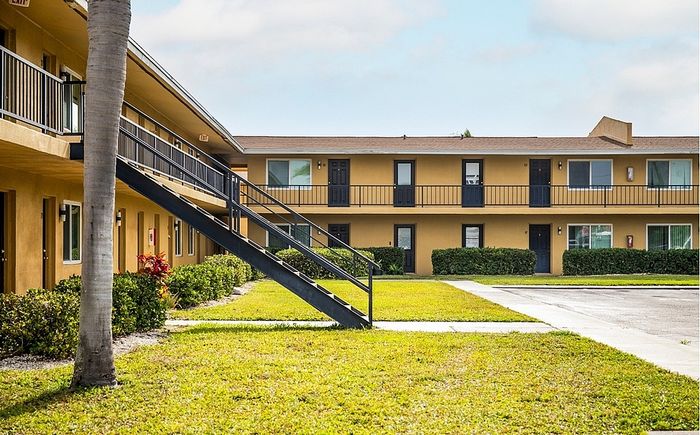Modern apartment complex with manicured landscaping, featuring stylish two-story design, inviting walkway, and lush greenery.