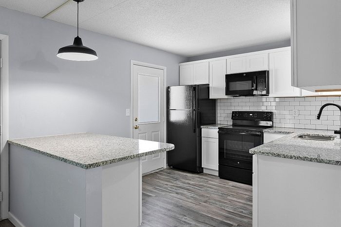 Modern kitchen with sleek granite countertops, stylish pendant lighting, and stainless steel appliances.