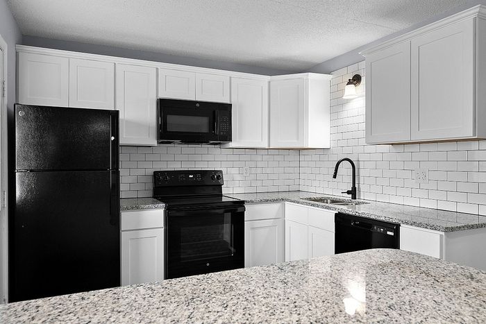 Modern kitchen with sleek black appliances, elegant granite countertops, and white cabinetry for a sophisticated look.