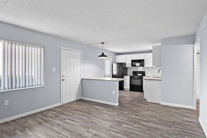 Bright and modern open-concept kitchen with sleek appliances, ample counter space, and elegant wood flooring.