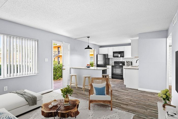 Bright and inviting open-concept living space with modern kitchen, stylish decor, and natural light streaming through large windows.