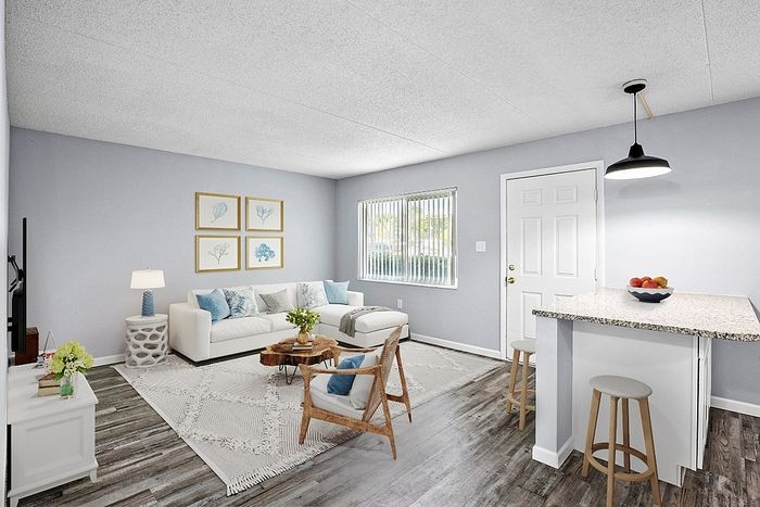 Inviting living room with serene blue accents, modern furnishings, and a cozy breakfast bar, bathed in natural light.