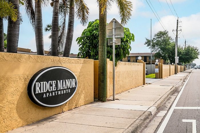 Inviting exterior of Ridge Manor Apartments with palm trees and a welcoming pathway.