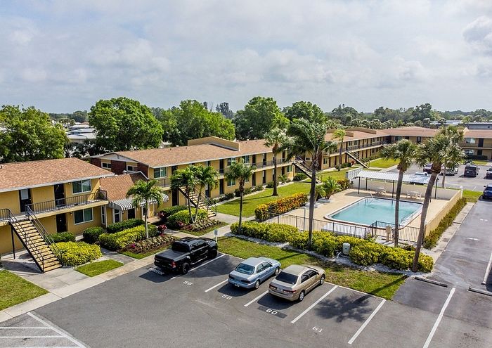 Charming apartment complex with lush landscaping, a sparkling pool, and ample parking, ideal for comfortable suburban living.