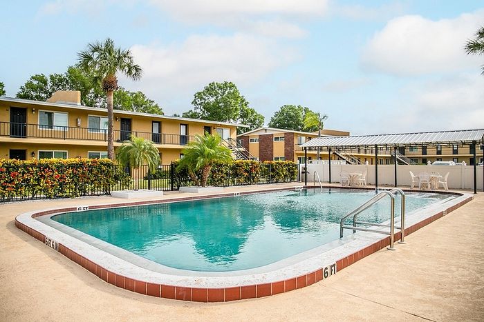 Inviting apartment complex pool area surrounded by lush greenery and modern building exterior.