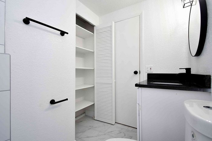 Modern bathroom featuring sleek black fixtures, elegant open shelving, and a stylish countertop for a chic aesthetic.