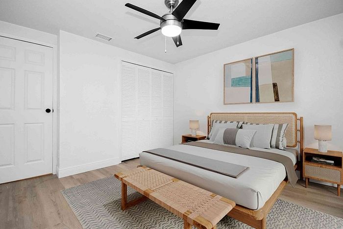 Inviting bedroom with modern ceiling fan, cozy double bed, stylish nightstands, and elegant minimalist decor.