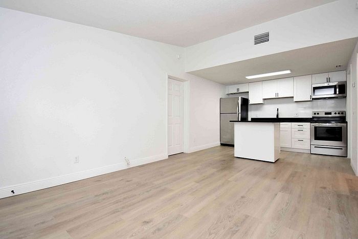 Modern open-concept kitchen with sleek stainless steel appliances and elegant wood flooring.