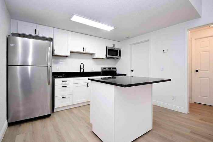 Modern kitchen with sleek stainless steel appliances, elegant black countertops, and crisp white cabinetry.
