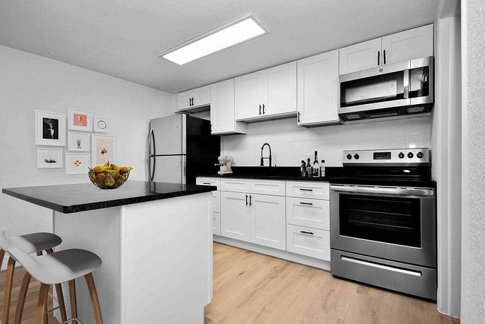 Sleek modern kitchen with elegant white cabinets, stainless steel appliances, and a chic black countertop island, perfect for contemporary living.