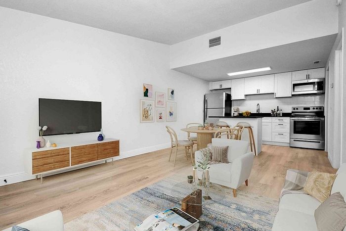 Chic open-concept living room and kitchen with stylish decor, featuring modern appliances, cozy seating, and elegant wooden flooring.