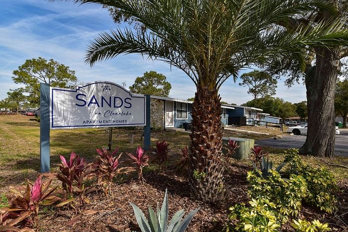 Inviting entrance to The Sands on Clearlake Apartment Homes with lush landscaping and a welcoming sign.