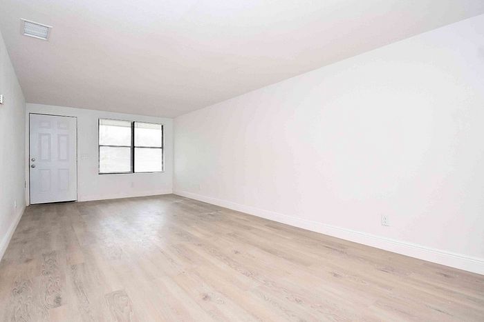 Bright and spacious empty living room with large windows and elegant hardwood floors, perfect for personalizing your new home.