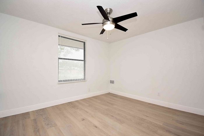 Bright, airy room with sleek ceiling fan and elegant wood flooring, perfect for creating a cozy living space.