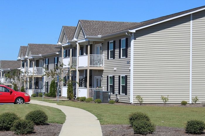 Modern apartment building with charming balconies, lush green landscaping, and a bright, welcoming facade.