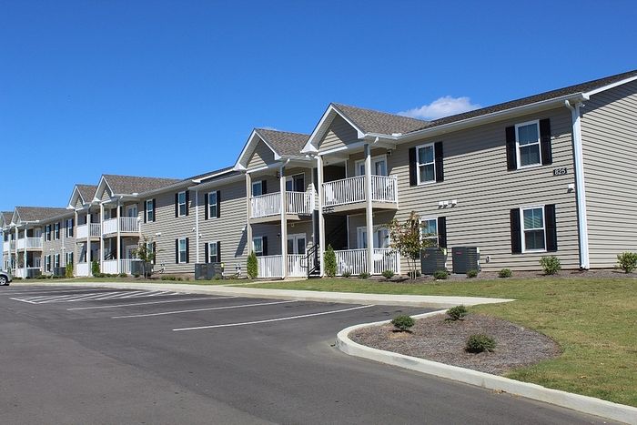 Charming two-story apartment building with inviting balconies and well-maintained surroundings under a clear blue sky.