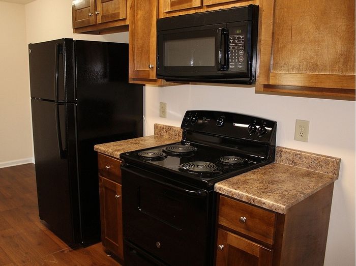 Modern kitchen with sleek black appliances, warm wooden cabinets, and elegant granite countertops.