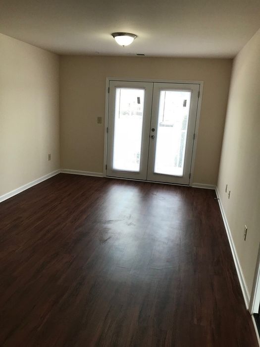 Inviting room with elegant dark wood flooring and natural light streaming through glass doors.