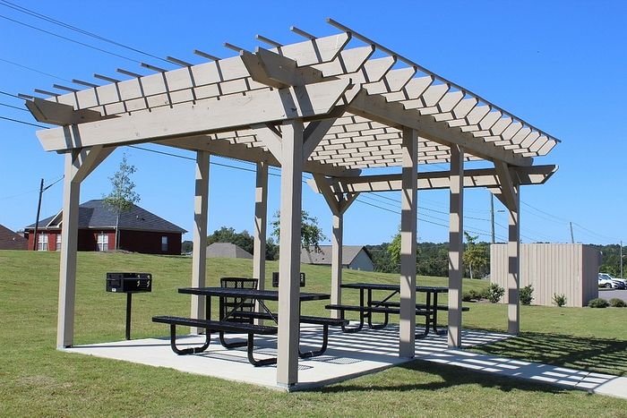 Charming outdoor pergola with picnic tables, perfect for relaxation and gatherings in a scenic green space.