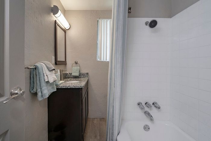 Contemporary bathroom with sleek granite countertop, elegant lighting, and a relaxing bathtub.