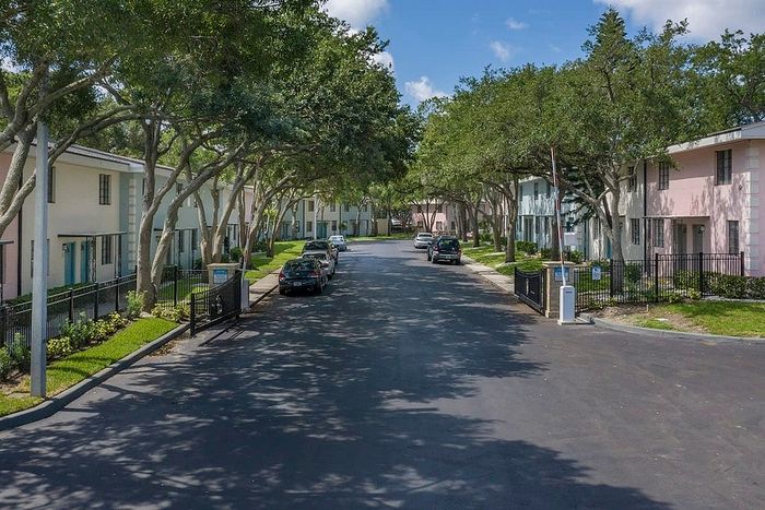 Charming suburban street lined with lush trees and colorful townhouses, offering a serene residential vibe.
