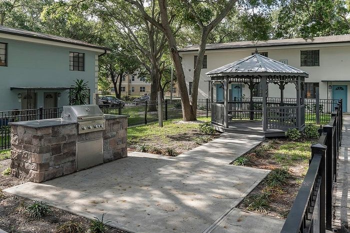 Charming outdoor space featuring a modern BBQ grill and a picturesque gazebo, surrounded by lush greenery.