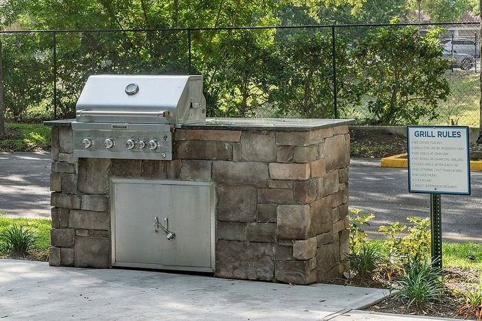 Charming outdoor stone grill with sleek stainless steel features, perfect for community gatherings and barbecues.