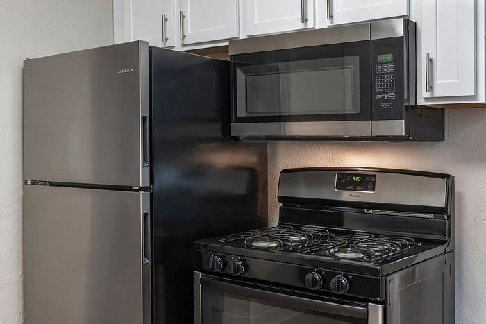 Modern kitchen with sleek stainless steel refrigerator and microwave above a stylish gas stove.