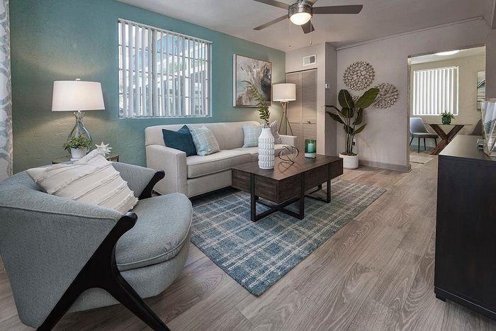 Chic living room with modern decor, featuring a comfortable beige sofa, elegant armchair, stylish coffee table, and vibrant teal accent wall.