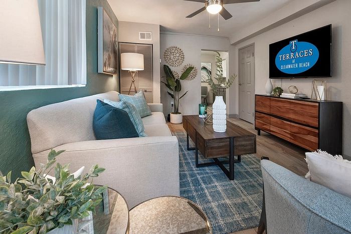 Inviting living room with modern decor, featuring a cozy sofa, chic accent pillows, and elegant wooden furnishings at Terraces Clearwater Beach.