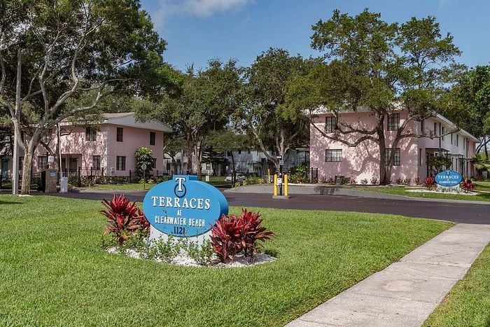Charming apartment complex with pastel pink buildings and lush green landscaping at Terraces at Clearwater Beach.