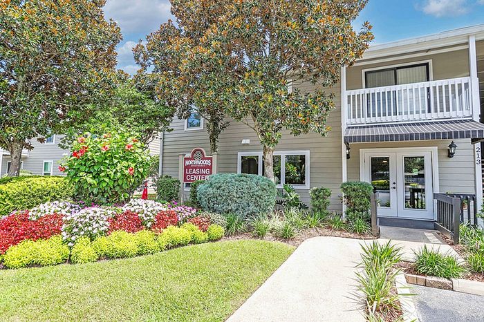 Charming apartment leasing center surrounded by lush greenery and vibrant floral landscaping, promising a welcoming atmosphere.