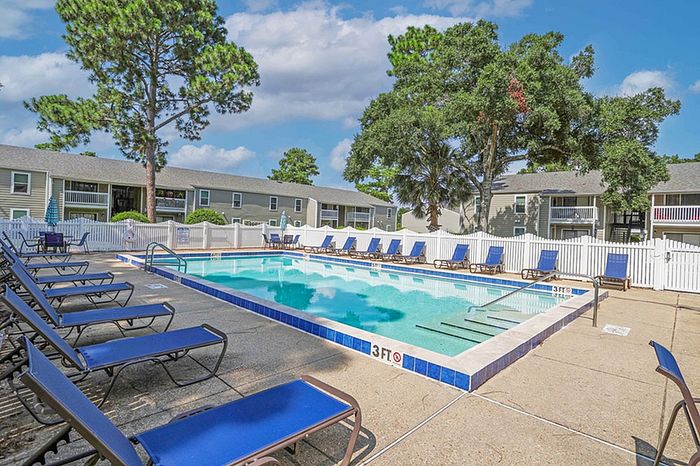 Inviting outdoor pool area surrounded by blue lounge chairs and lush greenery, perfect for relaxation and leisure.