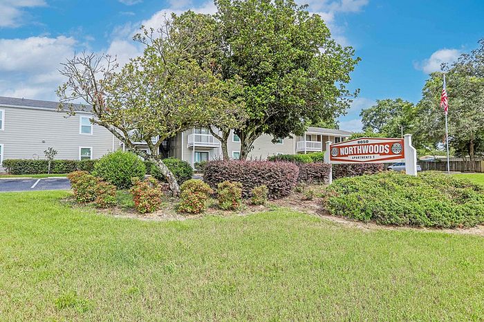 Charming Northwoods Apartments with lush greenery and welcoming entrance sign, showcasing modern living spaces in a serene environment.