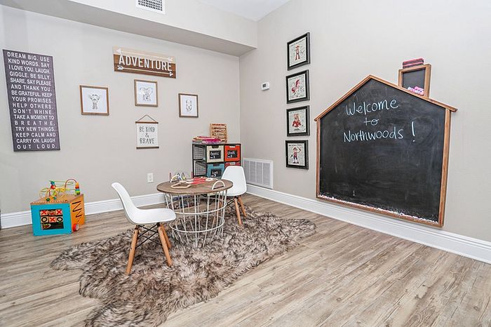 Charming playroom with cozy decor, featuring a house-shaped chalkboard, stylish seating, and playful art for imaginative adventures.
