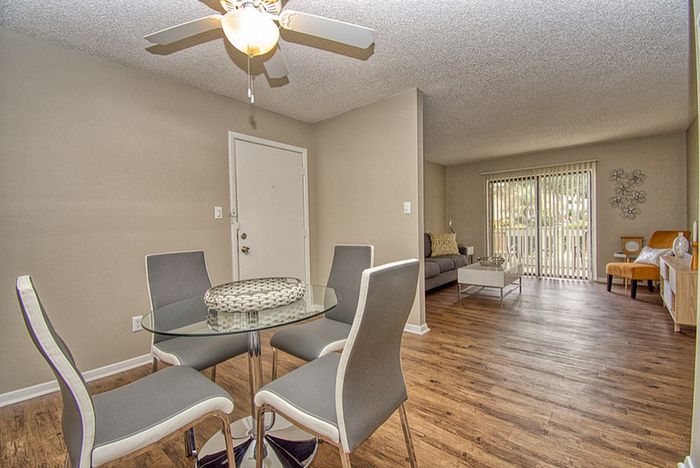 Modern open-plan living space featuring elegant dining area with stylish chairs, cozy lounge with a sofa, and floor-to-ceiling windows for natural light.