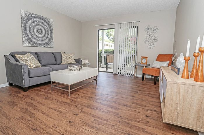 Inviting living room with elegant hardwood flooring, modern gray sofa, and chic decor accents offering a stylish ambiance.