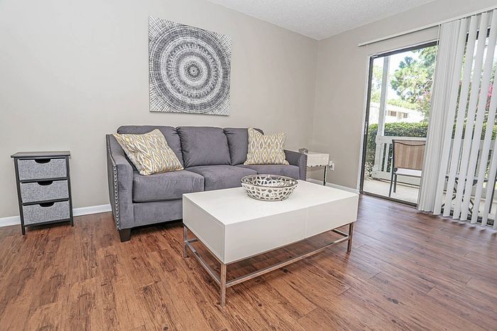 Inviting living room with chic grey sofa, modern coffee table, and bright natural light from a large window overlooking lush greenery.