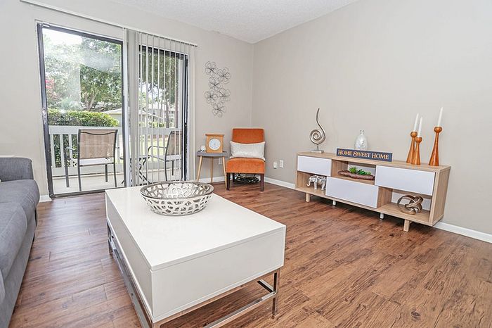 Bright and inviting living room with modern decor, featuring a cozy armchair, sleek coffee table, and expansive glass doors leading to a lush outdoor view.