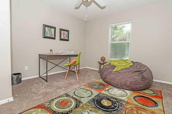 Cozy home office featuring modern desk, bright decor, and oversized bean bag chair for relaxation.