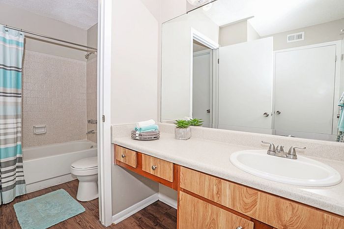 Modern bathroom featuring elegant wooden cabinetry, a sleek countertop, and a full-size bathtub with stylish tile surround.