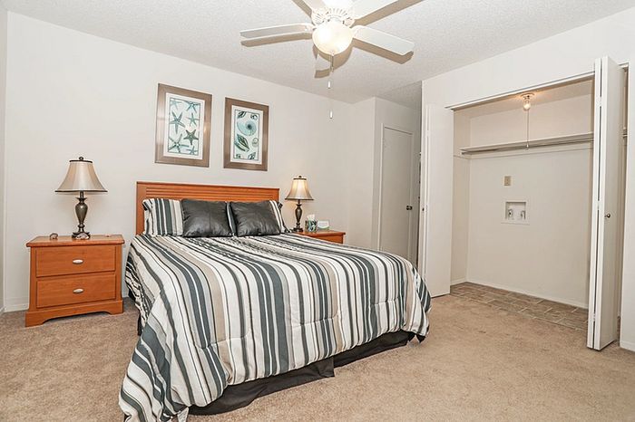 Inviting bedroom with modern striped bedding, elegant bedside tables, and a spacious open closet.