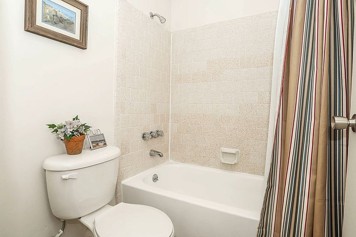 Bright and inviting bathroom featuring a classic white bathtub, elegant tiled walls, and colorful striped shower curtain for a touch of charm.