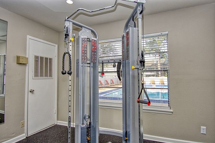 Modern apartment gym with high-tech fitness equipment and pool view, offering a refreshing workout experience.