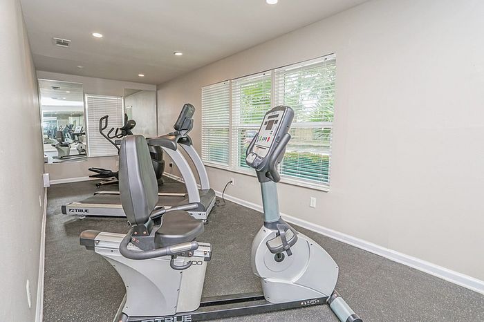 Bright and modern fitness room featuring state-of-the-art exercise machines and large windows for natural light.