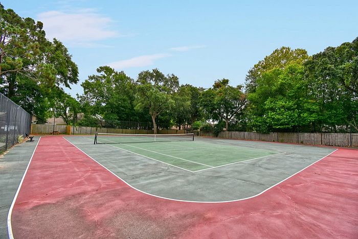 Vibrant outdoor tennis court surrounded by lush greenery, perfect for sports enthusiasts seeking a serene setting.